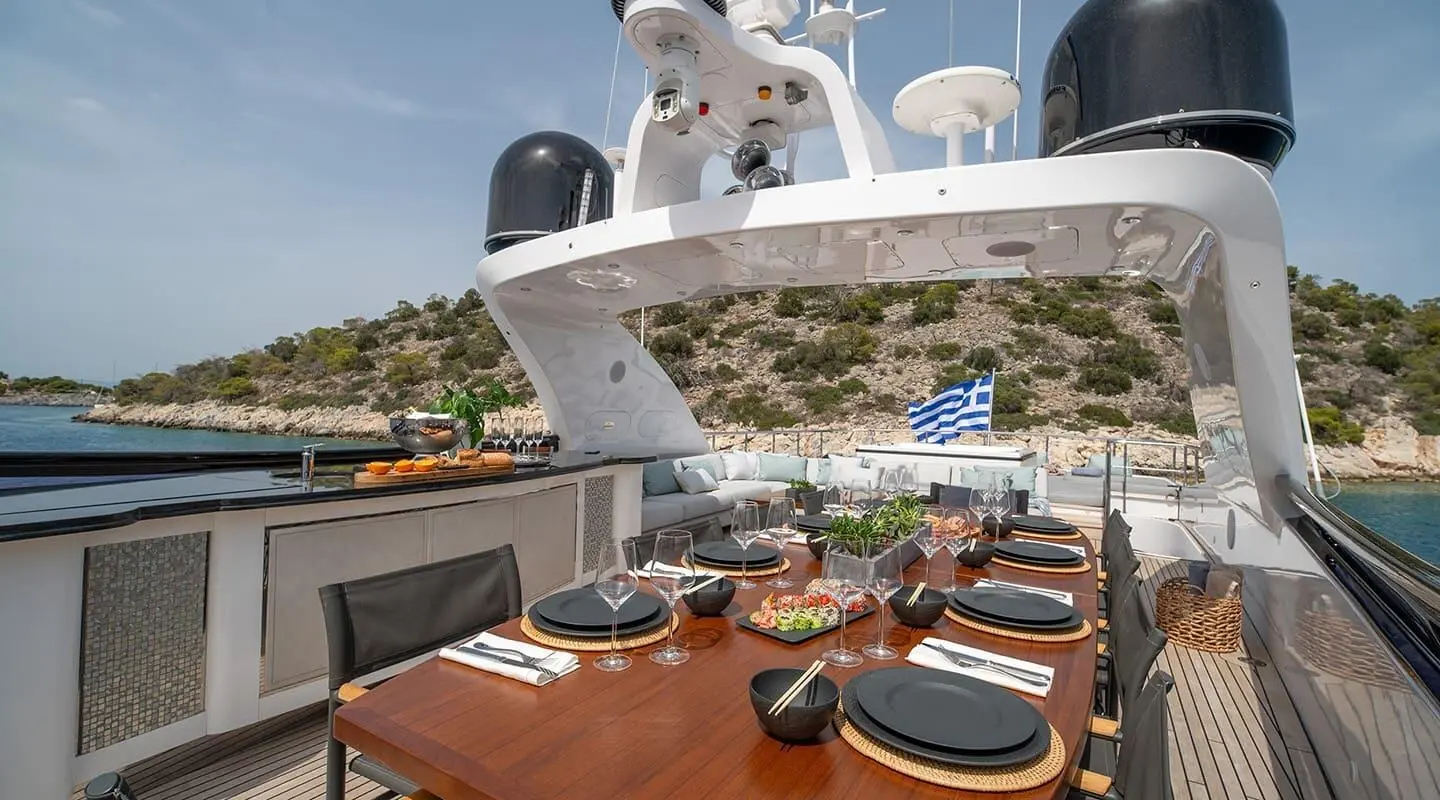 Pareaki II yacht dining setup on deck at sunset with plates and glasses