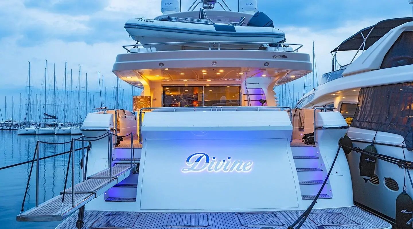 Divine yacht stern view in marina at dusk with illuminated name on stern