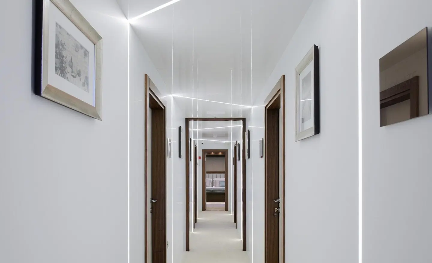 White-walled corridor of Corsario yacht with doors and framed pictures