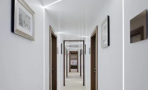 White-walled corridor of Corsario yacht with doors and framed pictures