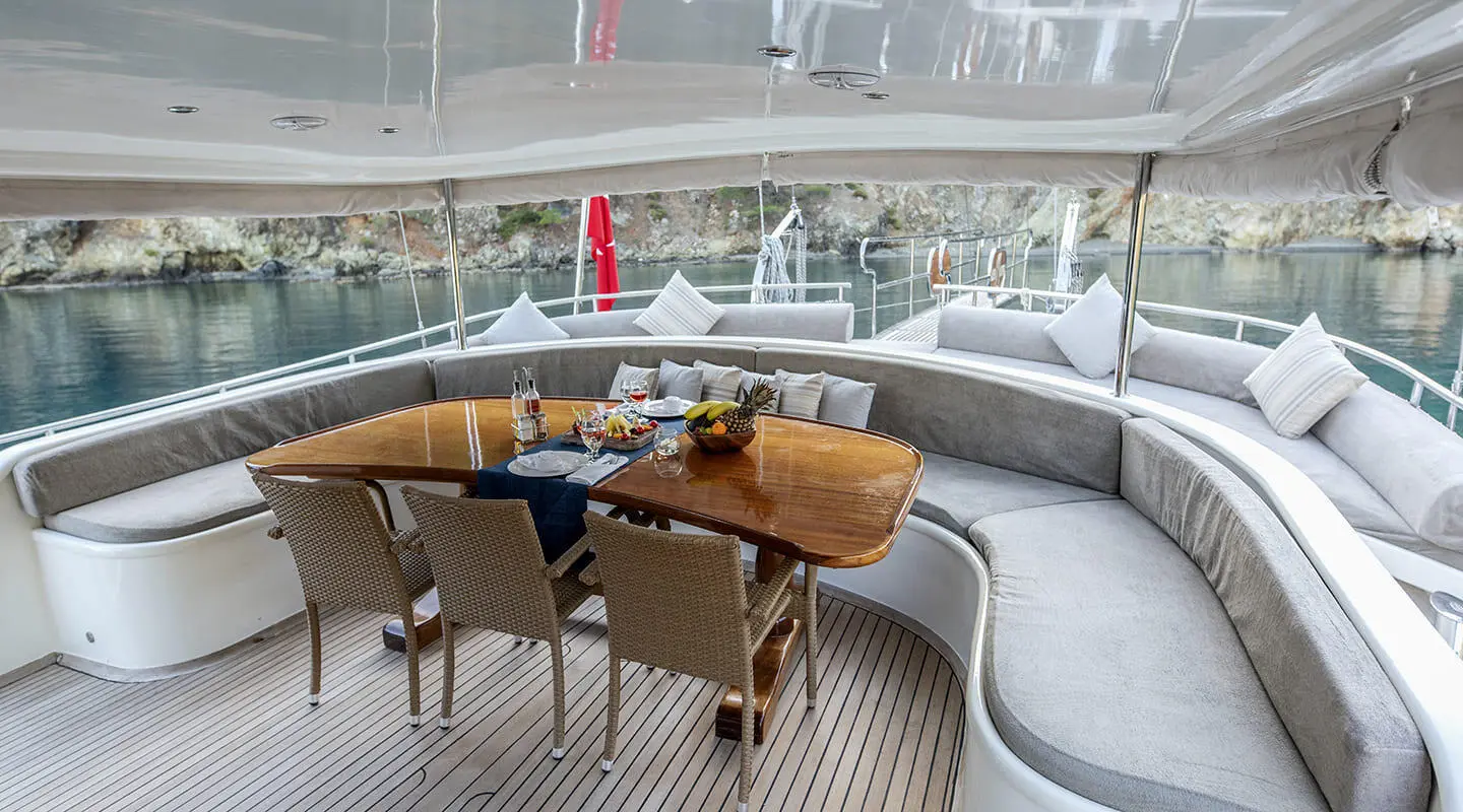 Kayhan 4 yacht lounge on deck with table, chairs, and sunset glow