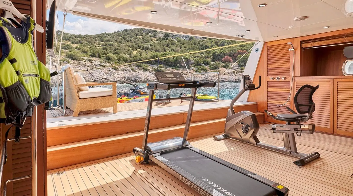 Mobius yacht treadmill deck with railing, ocean view, sunlit teak seating