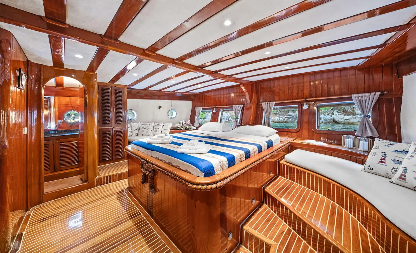 Elegant yacht Eleganza deck with polished wood, seating, and blue striped cushions at sunset