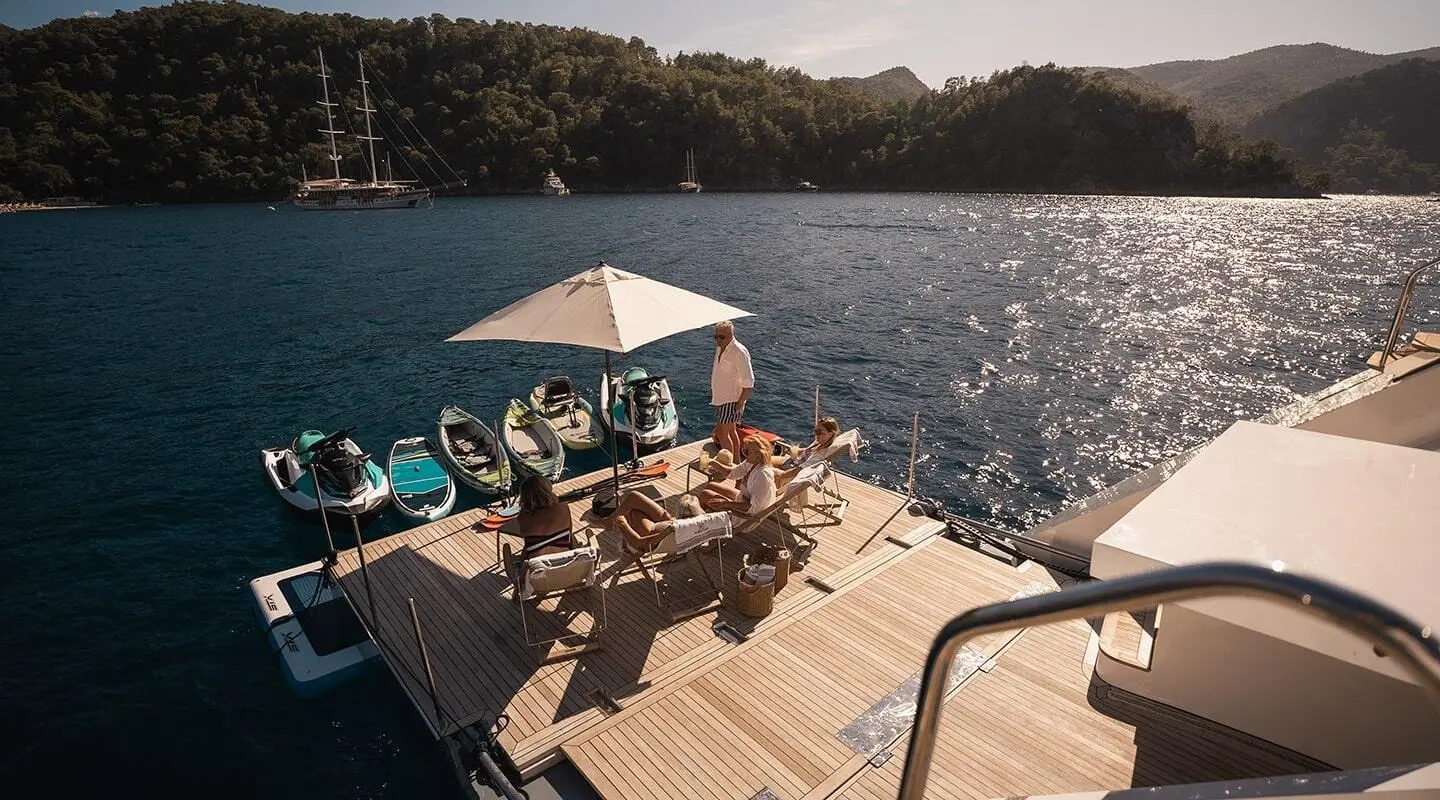 North Wind yacht charter: sunlit swim platform with people on deck by water