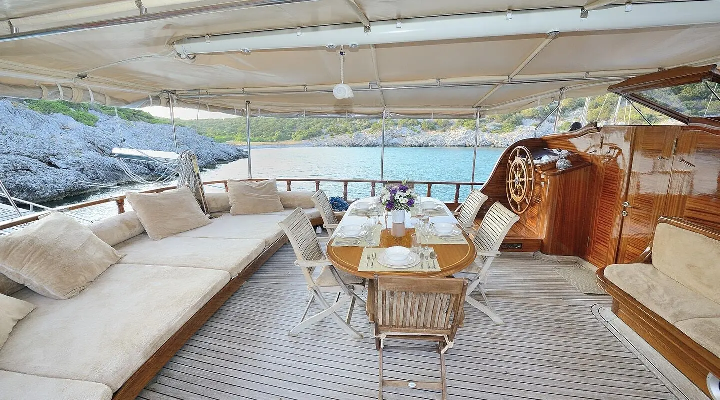 Samarkand luxury gulet deck with wooden table and chairs under canopy at sunset