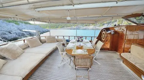 Samarkand luxury gulet deck with wooden table and chairs under canopy at sunset
