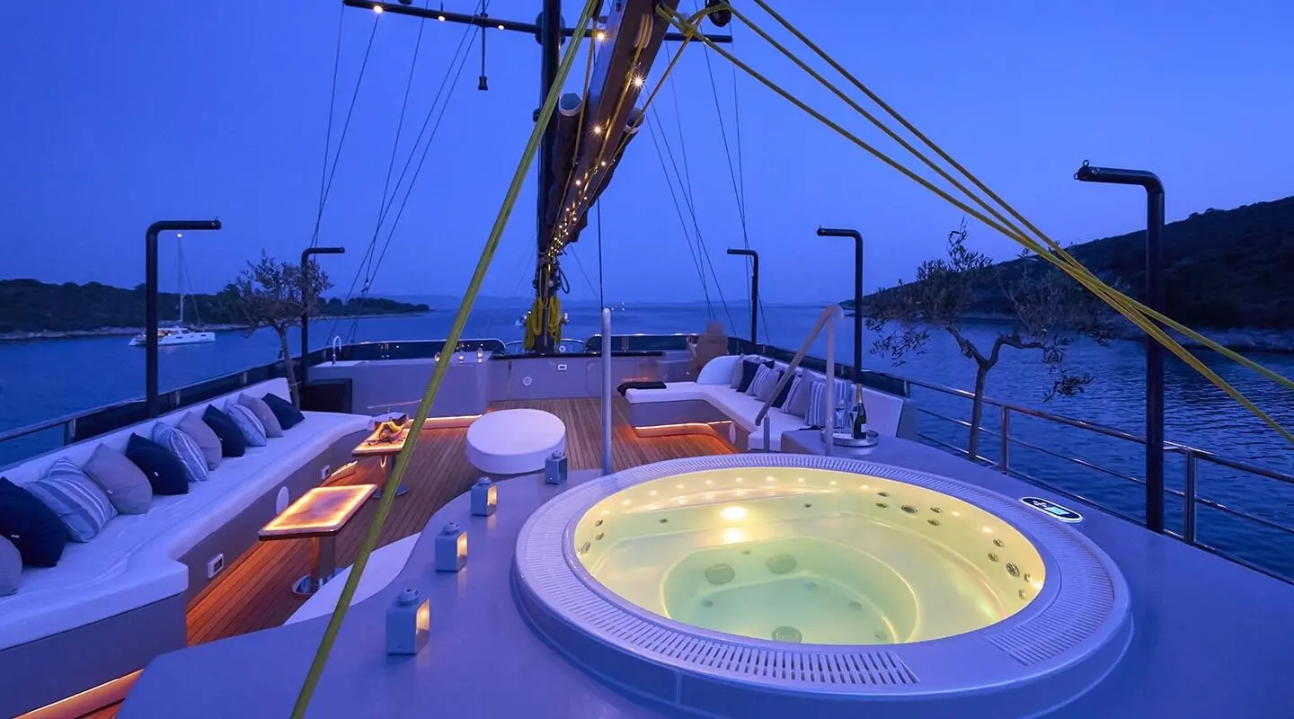 Yacht Rara Avis at sunset with hot tub on deck and sails in harbor