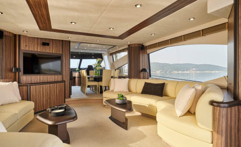 Luxurious interior with cream sofas, wood paneling, and large windows showing sea view