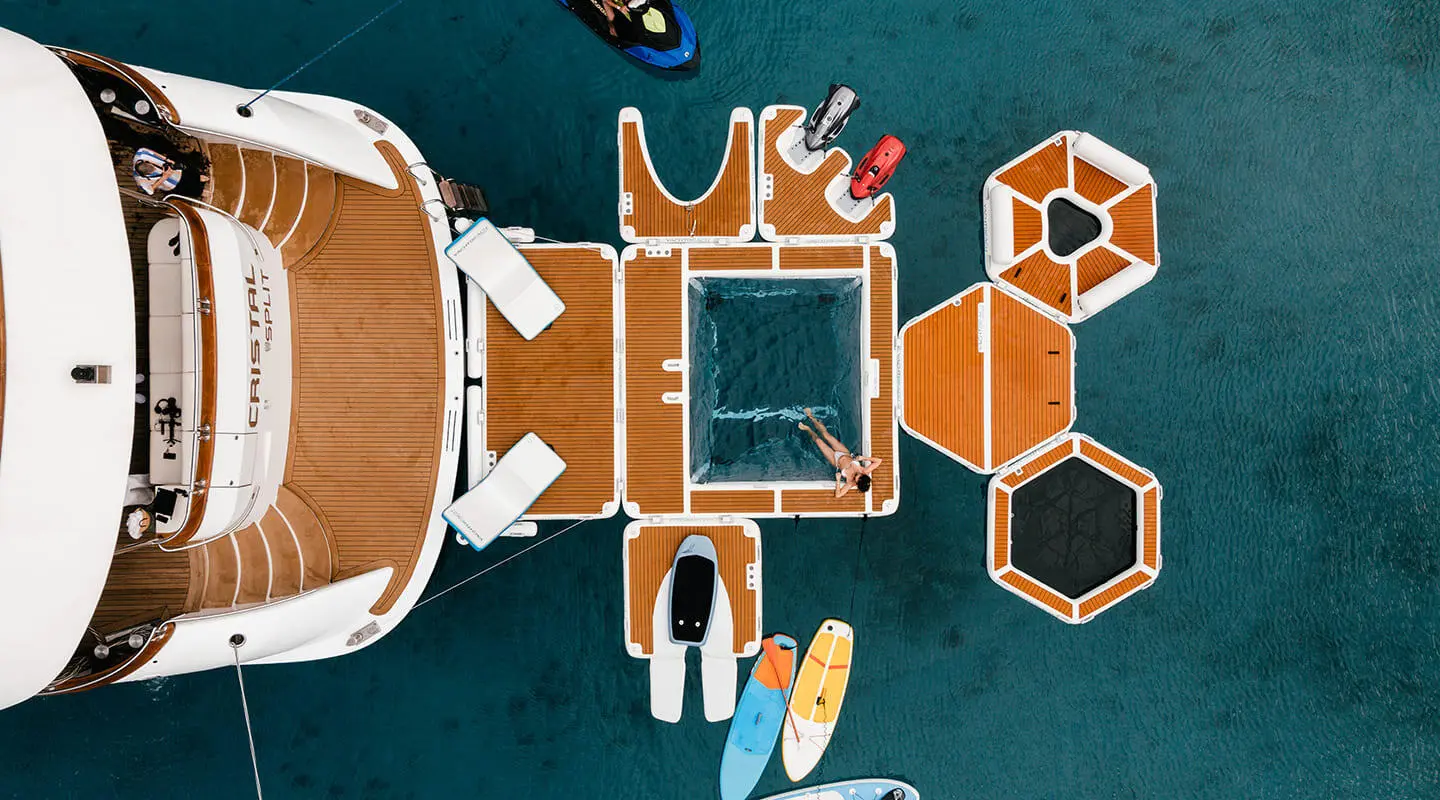Top-down view of Cristal yacht docked, surrounded by orange deck loungers and turquoise water