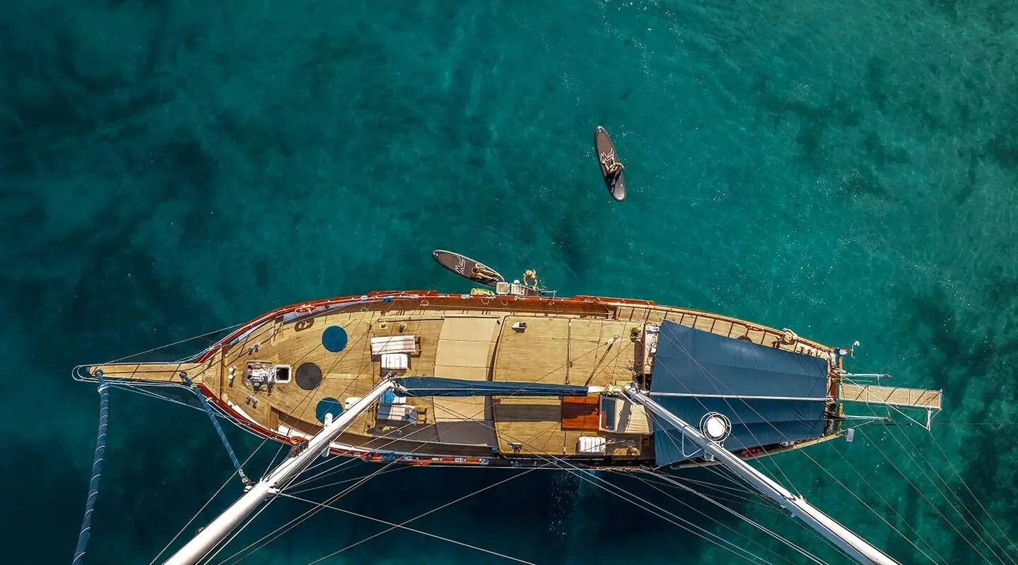 Top-down view of luxury yacht anchored in turquoise water at sunset