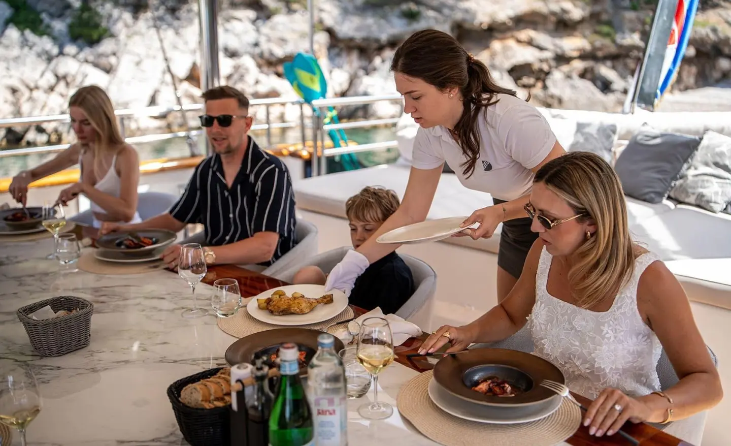 Dalmatino yacht dining: people seated around a table on deck with plates