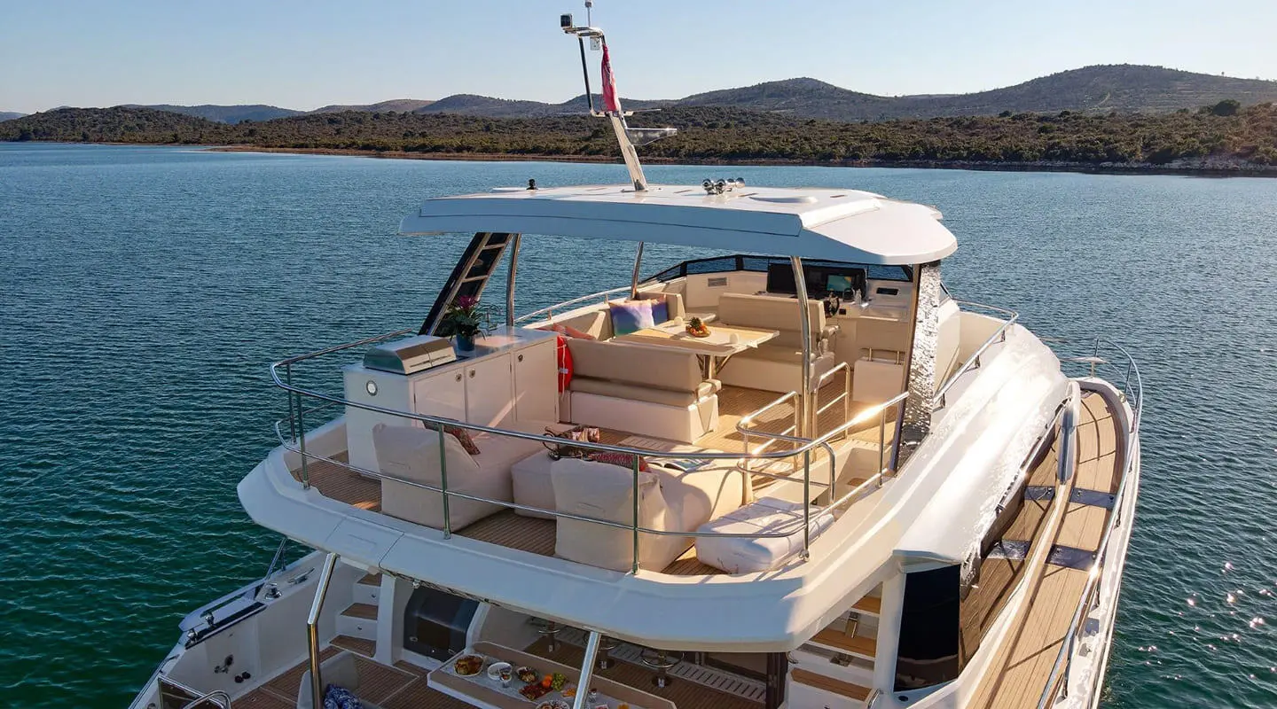 Yacht named By My Side docked on calm water at sunset with seating area