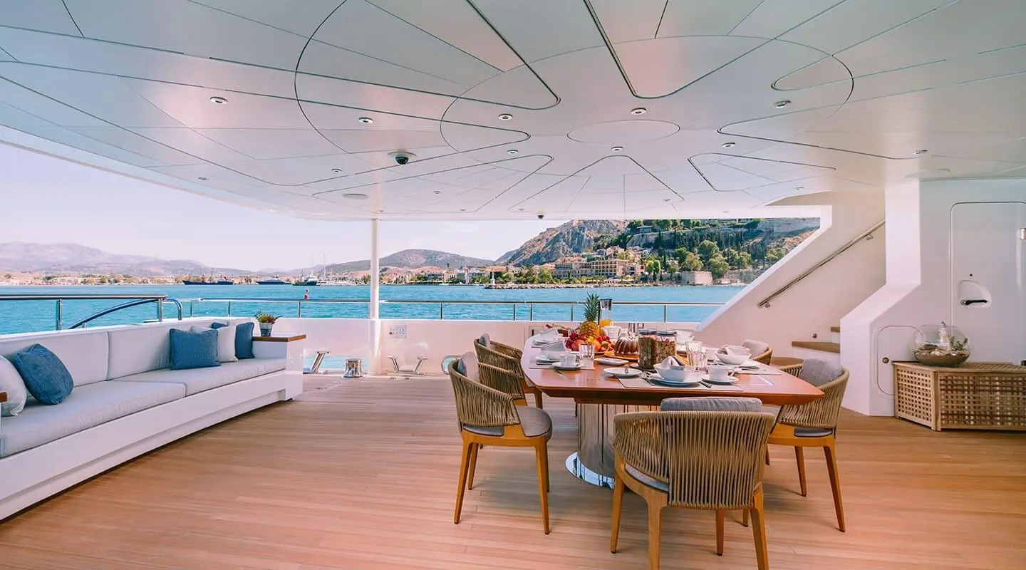 Xana motoryacht deck seating area with table and people overlooking blue water