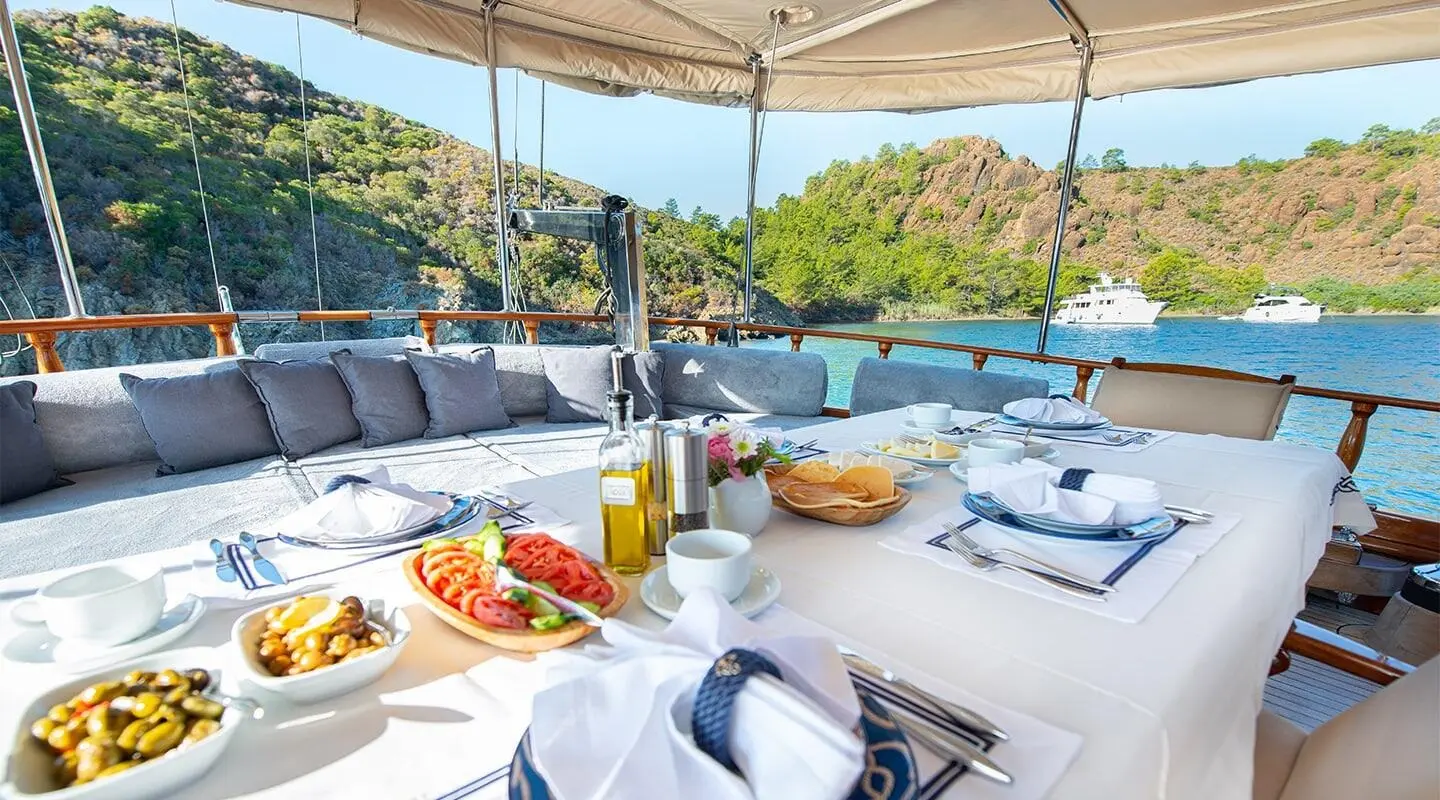 Ros Mare yacht charter lounge area with table setting on deck at sunset