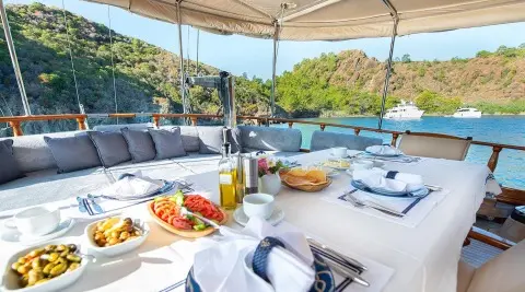 Ros Mare yacht charter lounge area with table setting on deck at sunset
