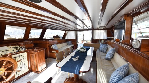 Luxurious gulet salon with long table, wood paneling and soft seating