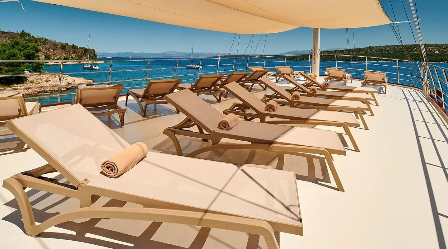 Luna yacht sun loungers on upper deck with sea and coastline scenery