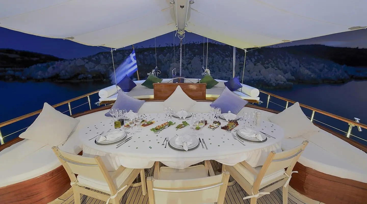 Dining area on aft deck of Ecce Navigo gulet with table set for meals