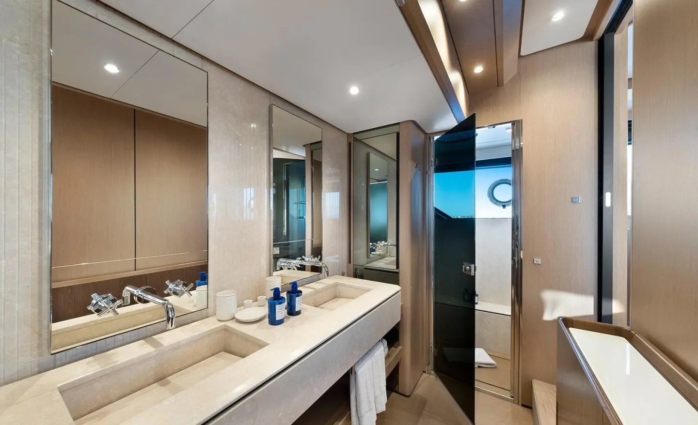 Luxury yacht bathroom with wide sink, wood paneling, and large mirrors