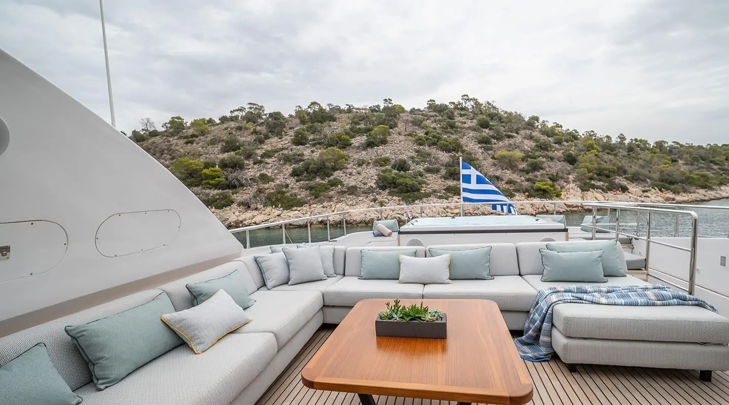 Pareaki II yacht yard terrace: white seating, coffee table, scenic coastline view