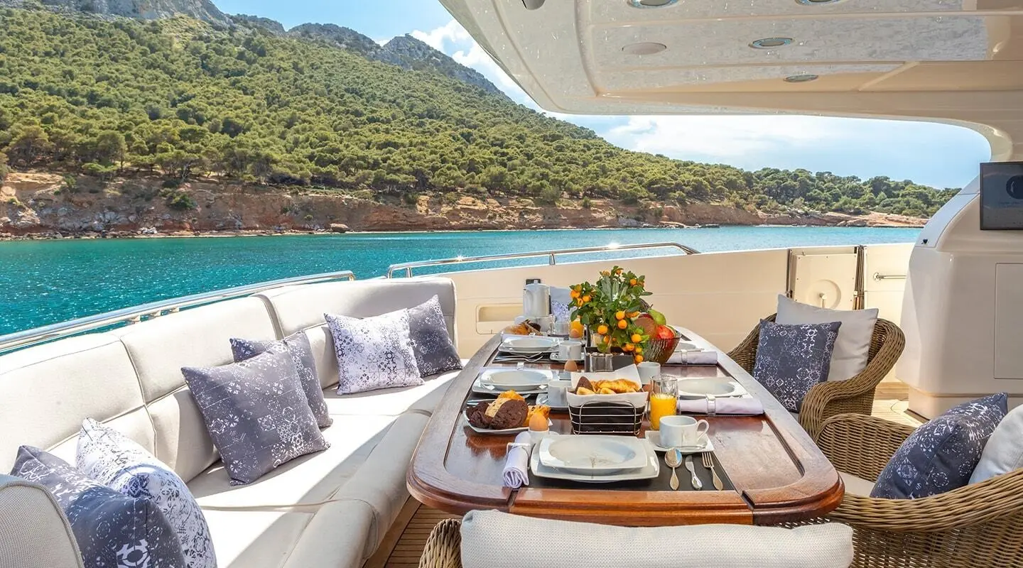 Dining table on a luxury yacht deck at sunset with plates and flowers