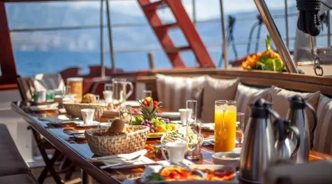 Romanca luxury gulet yacht dining setup at sunset with plates and drinks