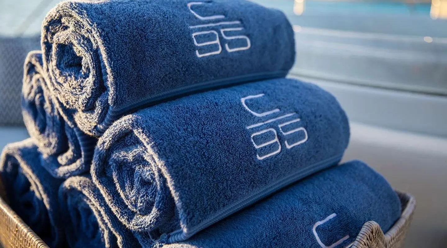 Close-up of stacked blue towels on a yacht deck in bright sunlight