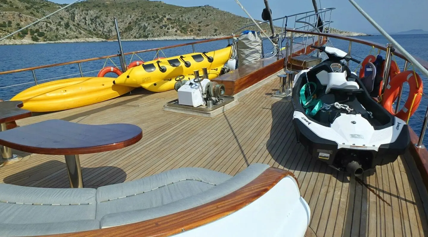 Sunset-lit yacht deck with yellow boat, blue water, and seating area