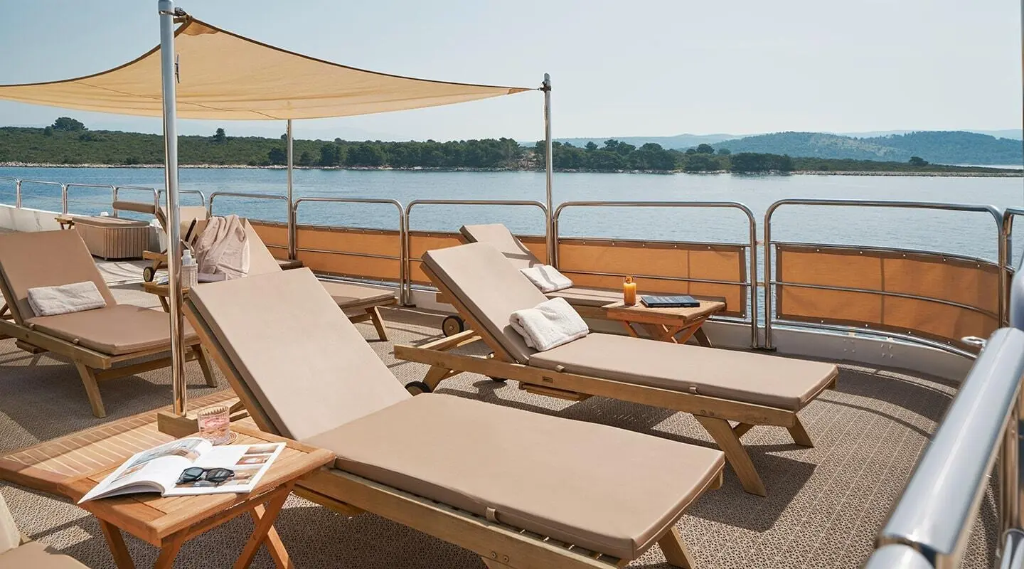La Perla yacht sunloungers on deck at sunset overlooking calm sea