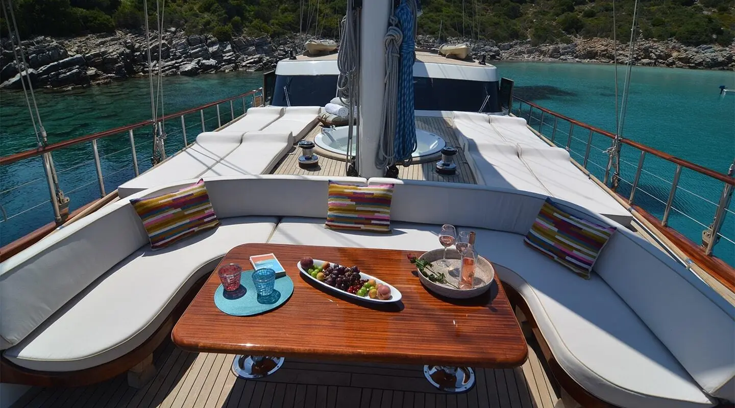 Gleaming wooden table with plates and cups aboard blue Heaven yacht, calm sea backdrop