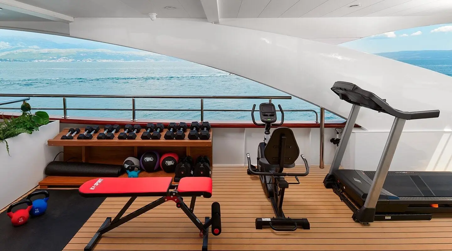 Ohana yacht gym deck area with people exercising near railing and water view