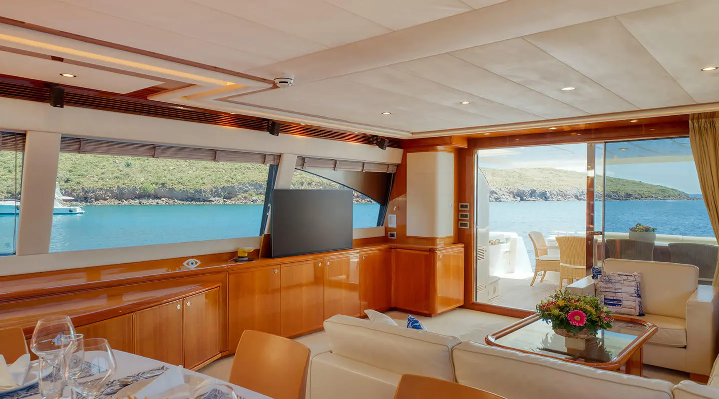 Lidia yacht interior: sunlit lounge with beige seating, wooden accents, large windows