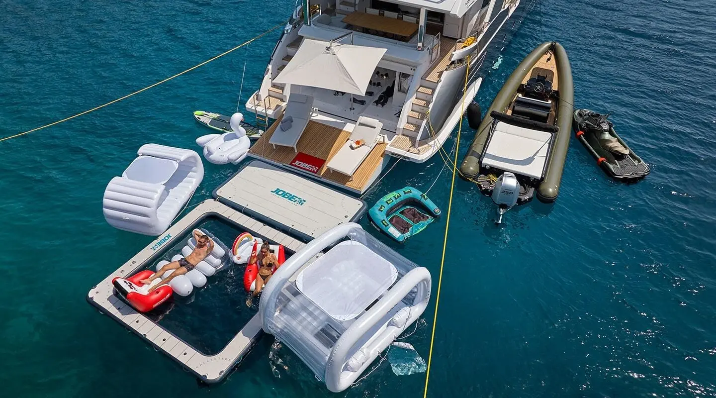 Aerial view of Aluminia Too yacht docked with multiple boats nearby in turquoise water