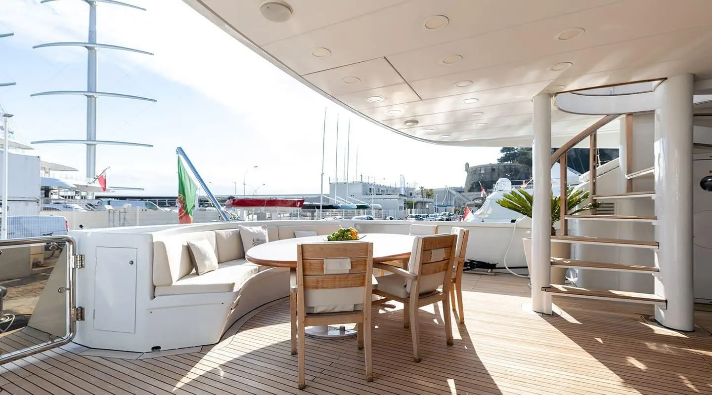 Yacht Brooklyn aft deck with table and chairs on sunny marina, other boats