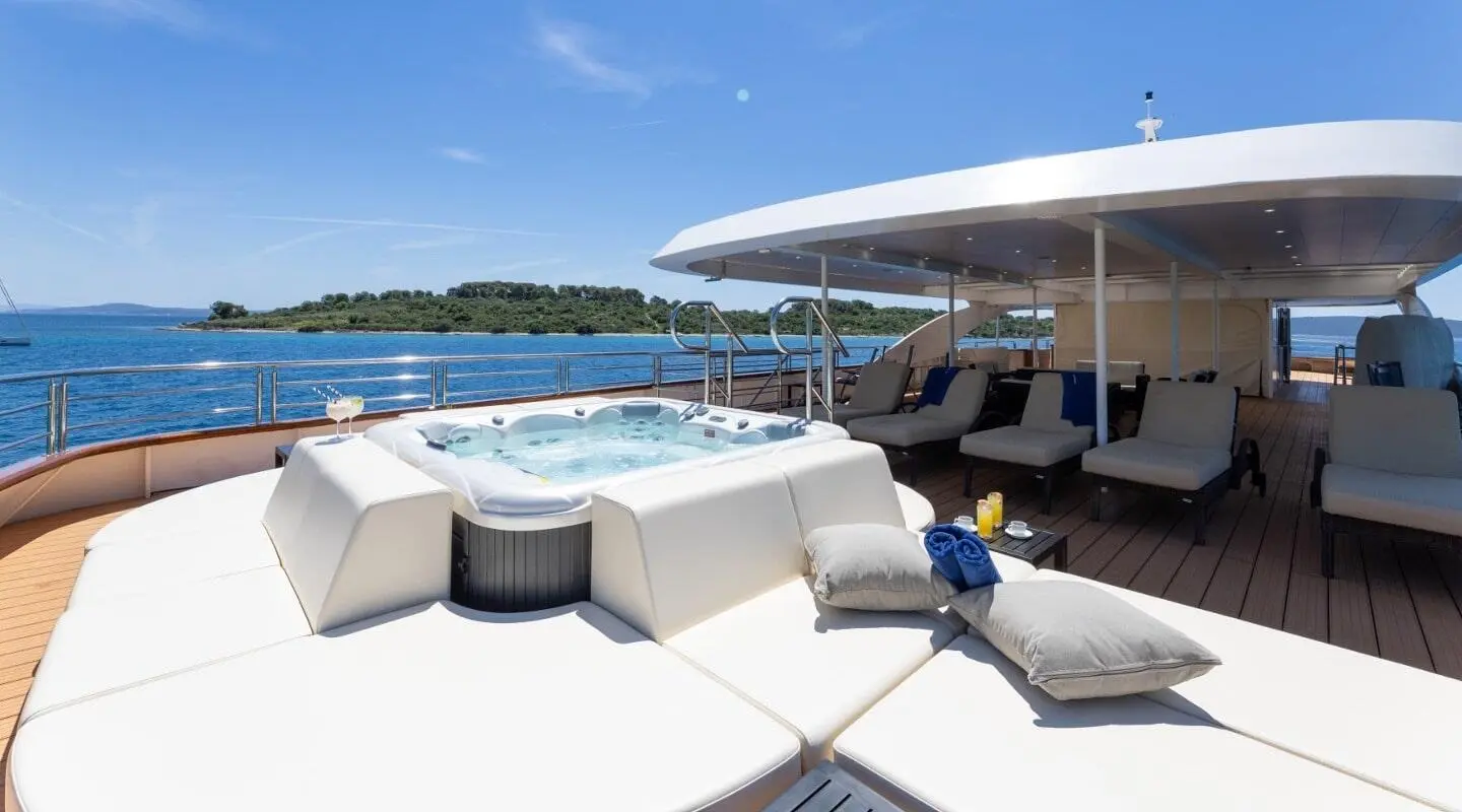 Queen Eleganza yacht deck at sunset with white seating and blue sea