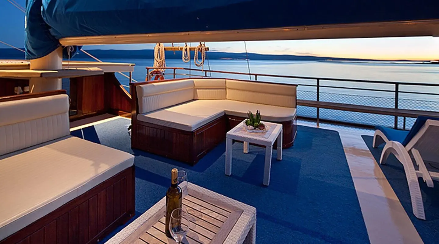 Gulvet deck seating with cushioned sofas and white tables on sunny yacht deck