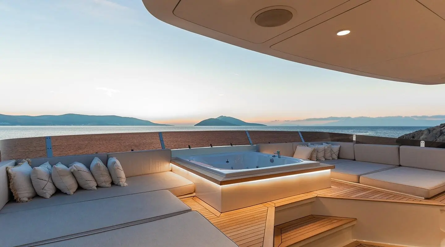 Illusion II yacht deck at sunset with wooden seating and calm sea view