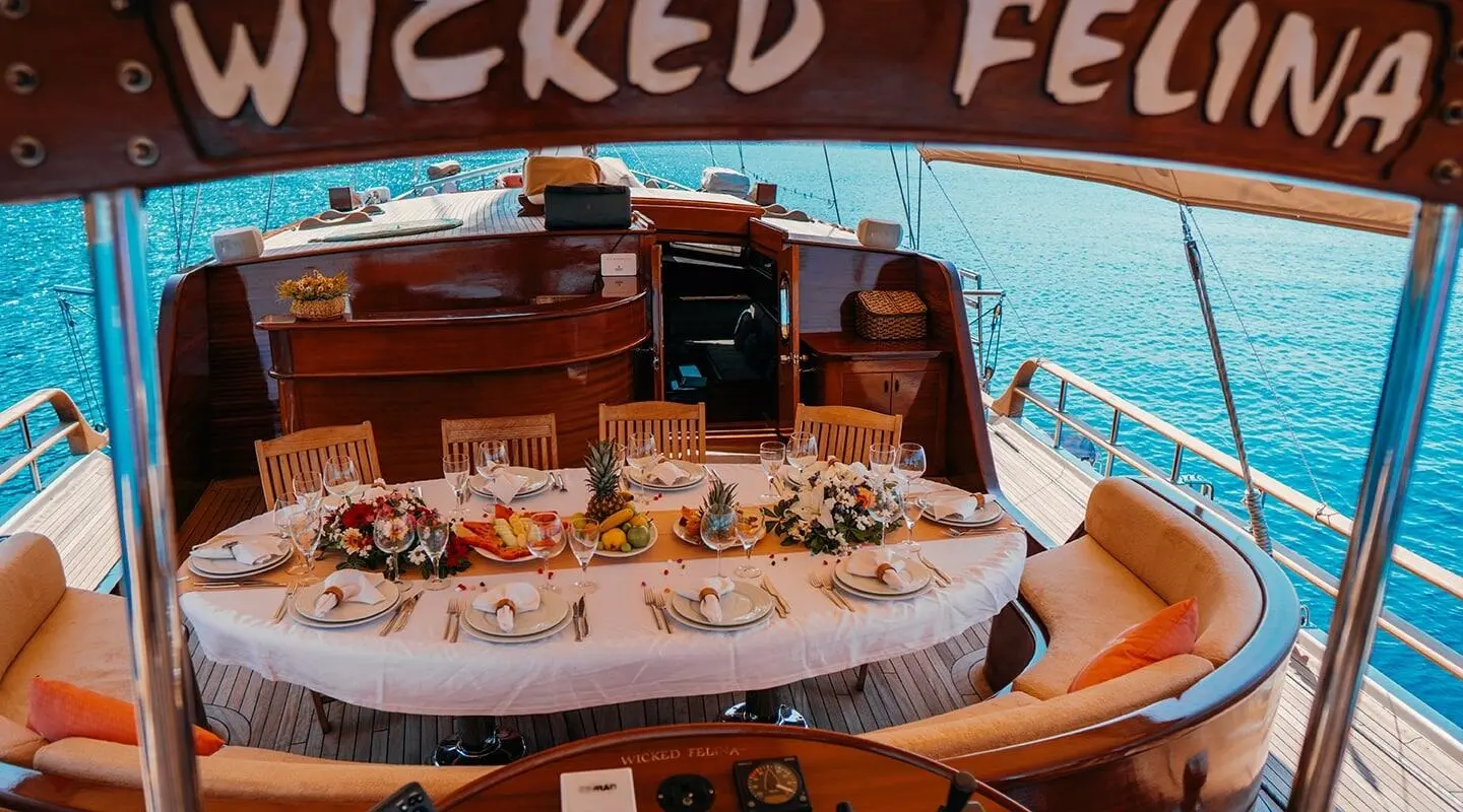 Elegant dining table on the aft deck of a luxury wooden yacht with blue sea