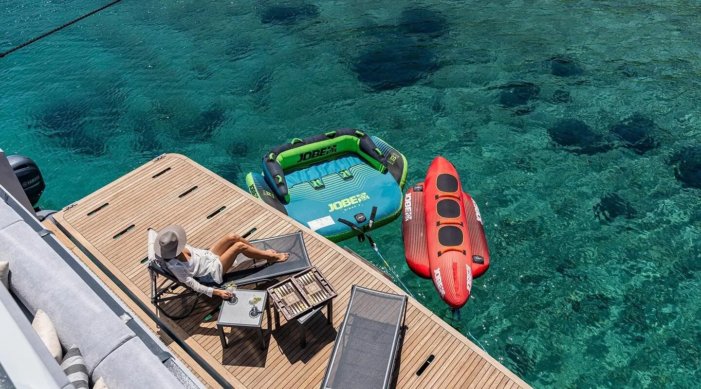 Aerial view of a yacht named Calm Down docked near a red and green inflatable kayak