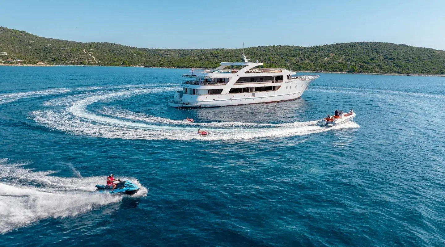 Karizma motor yacht cruising on blue water with small speedboat nearby