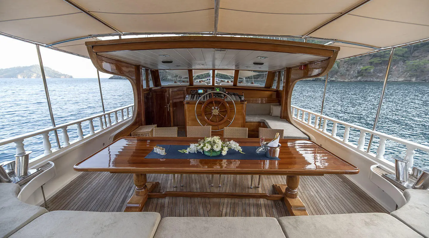 Kayhan 8 luxury yacht deck with polished wooden table and helm in view
