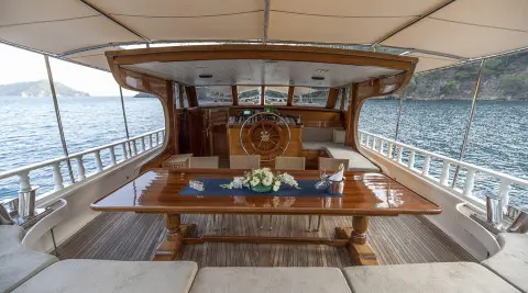 Kayhan 8 luxury yacht deck with polished wooden table and helm in view