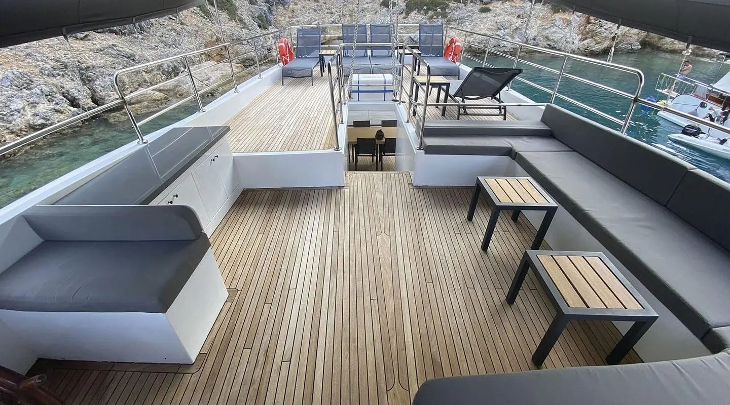 Maske 5 yacht deck with teak flooring, seating, and sunset lighting at harbor