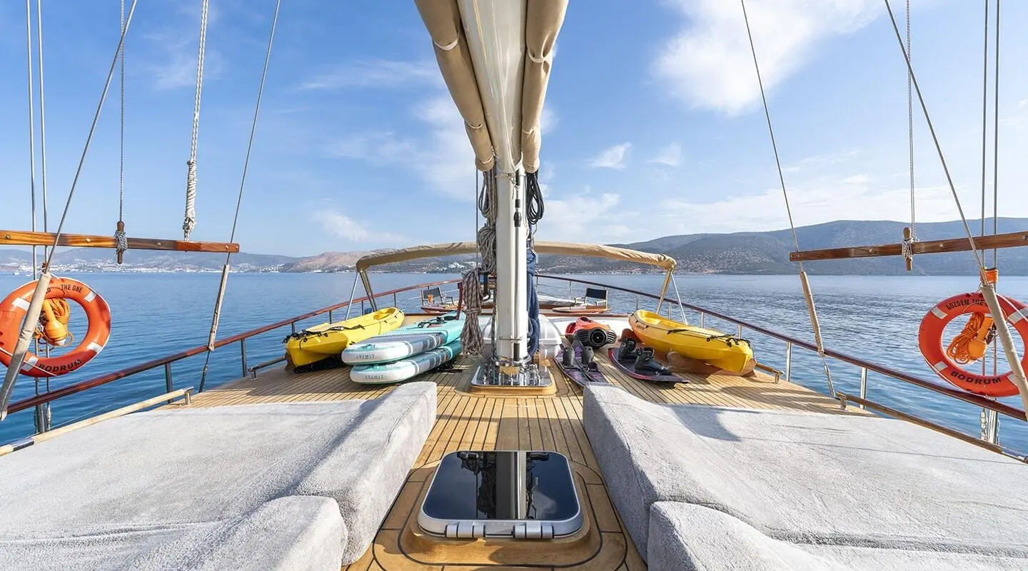 Deck view of a yacht with lounging yellow dinghies, calm sea, and clear sky