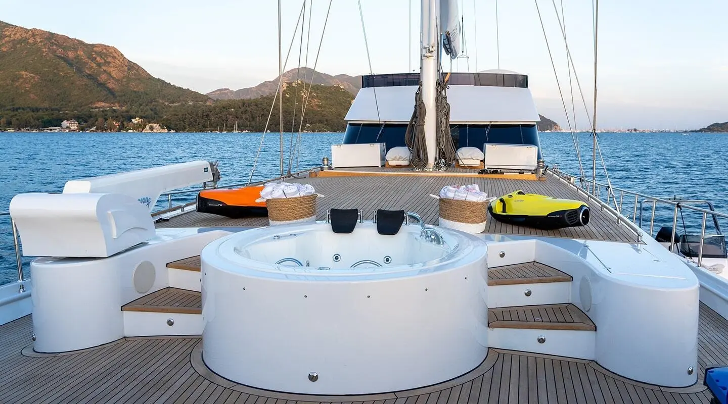 View of a white circular seating area on a yacht with masts and sunset in the background