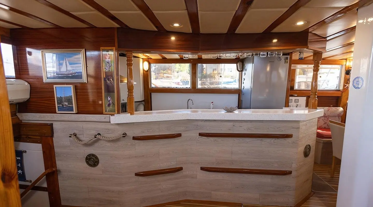 Gardelin yacht charter interior with cushioned seating and windows overlooking sunset sea