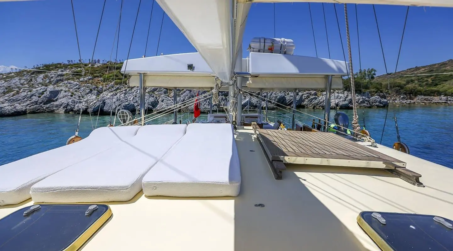 Gazella yacht deck with cushioned seating, sunshade sails, and calm marina view