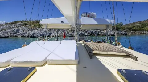 Gazella yacht deck with cushioned seating, sunshade sails, and calm marina view