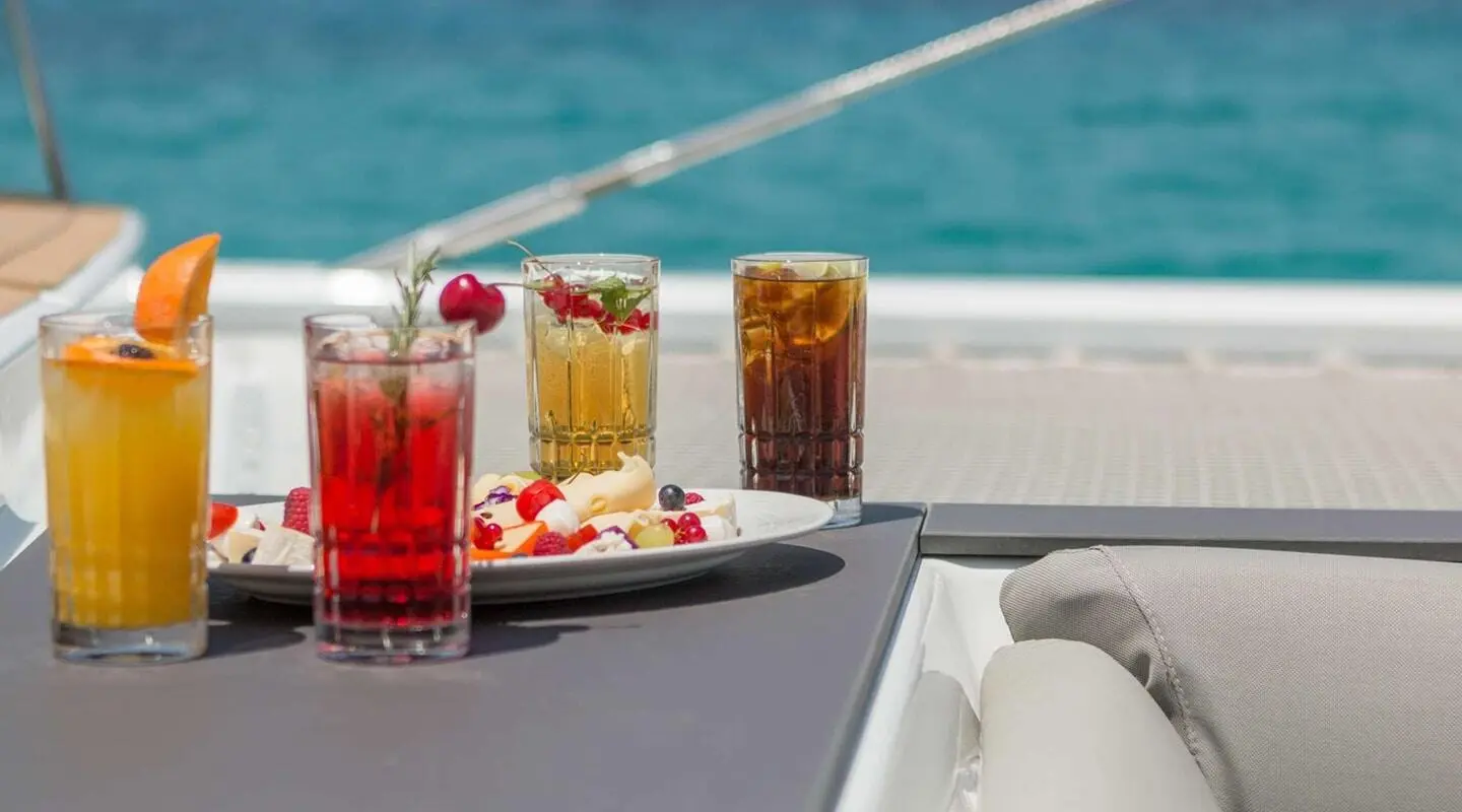 Assorted colorful cocktails and snacks on a yacht deck with blue sea in background