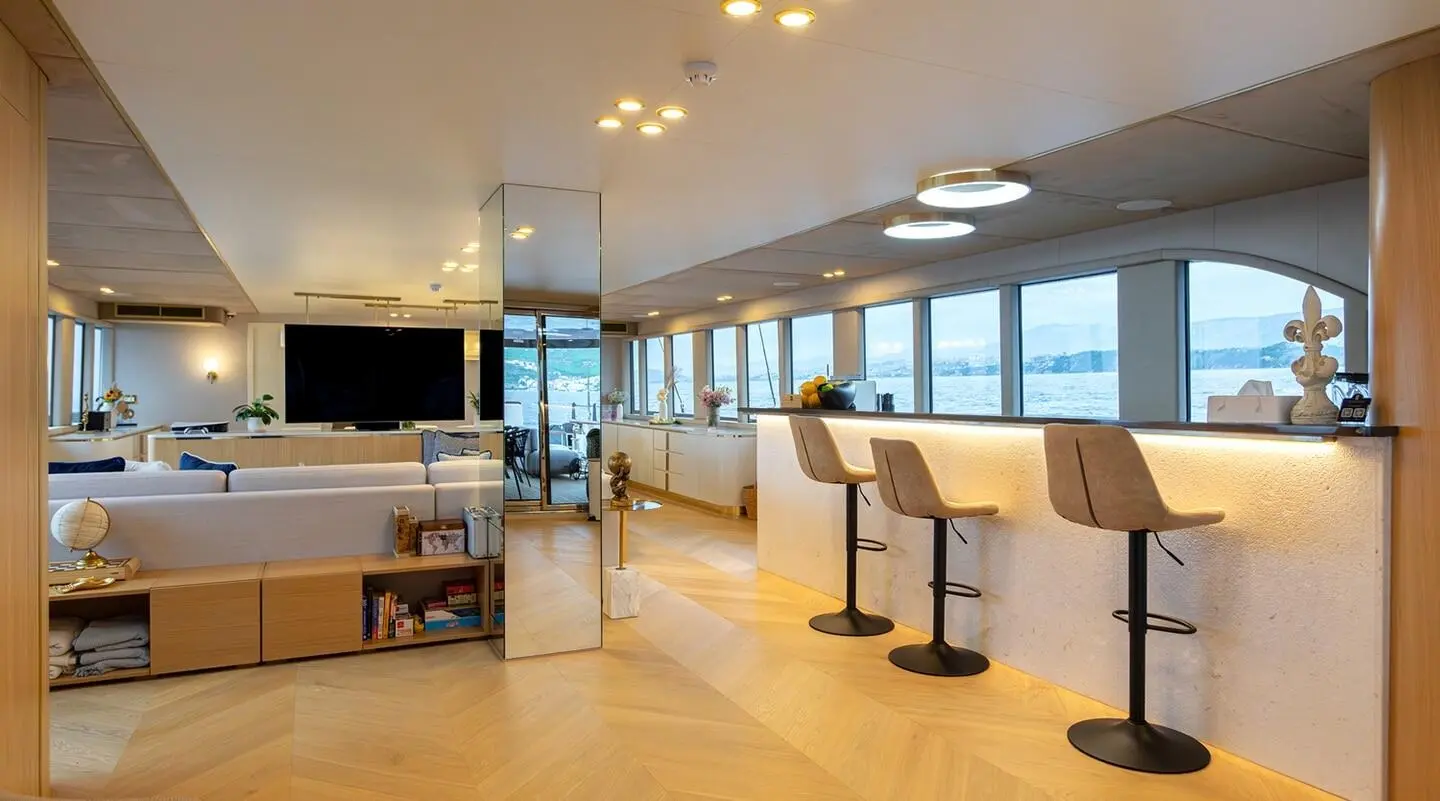 Interior salon with seating, TV, bar, and sea view windows